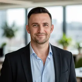 Professional headshot of a French man in his late 30s, natural light, modern office background slightly blurred, confident and approachable expression, business casual attire, realistic editorial photography, high resolution
